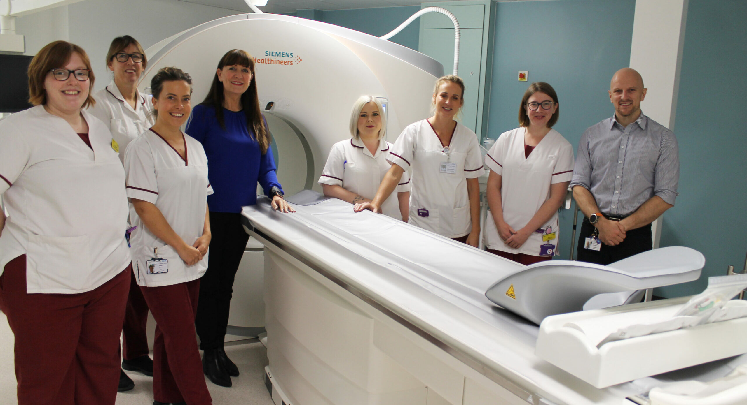 Radiology staff stand in front of a CT scanner